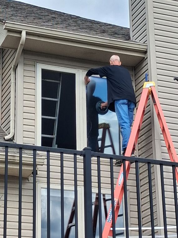 Charles on a ladder installing exterior door glass