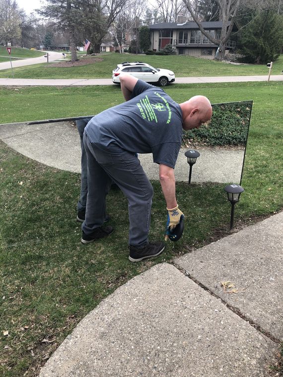 Charles carrying a large mirror across a customer's front lawn