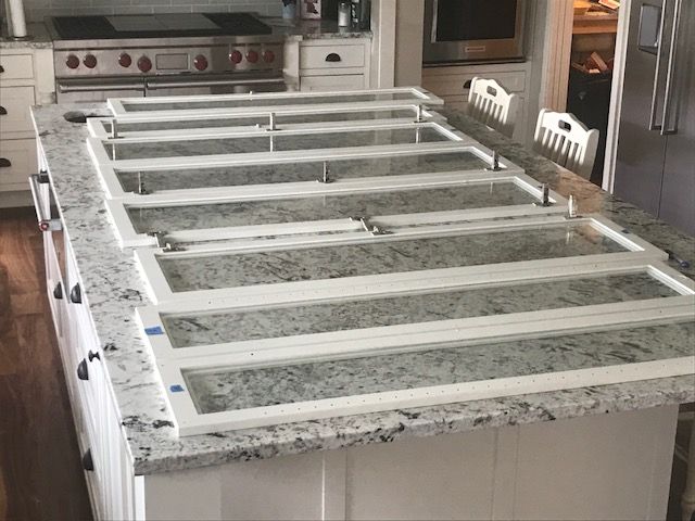 Glass panels laid out on a kitchen island for cabinet doors