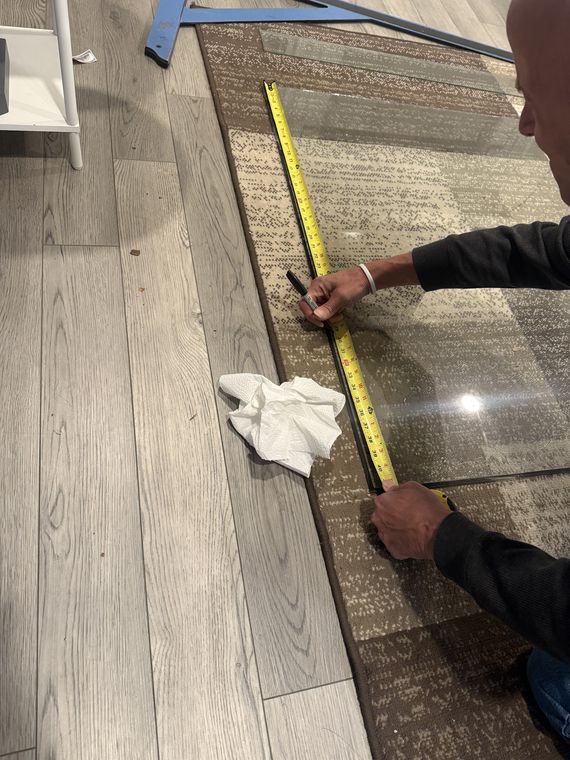 Measuring a pane of glass with a tape measure on the floor