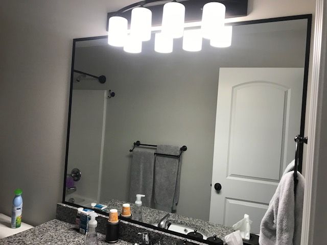 Black-framed mirror over a granite vanity