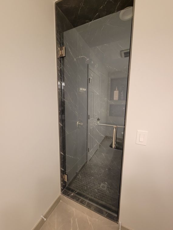 Frameless glass door on a dark marble shower