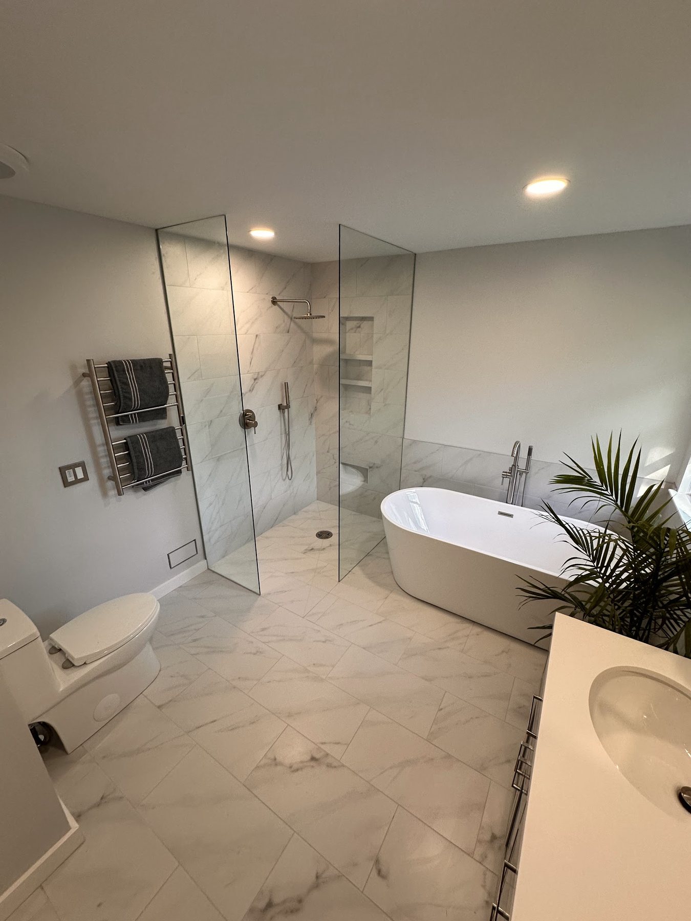 Frameless glass shower enclosure in a marble bathroom installed by A Affordable Glass & Mirror Co.