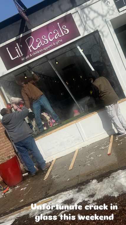 Broken storefront glass being cleaned up and boarded